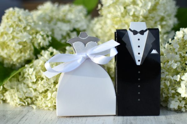 A bride and groom wedding favors in front of white hydrangeas. Generic couple
